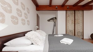 Una cama bien tendida con colcha gris y almohadas blancas, cabecera de madera y pared con diseños circulares.