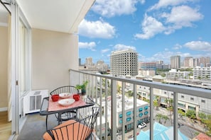 Un balcón con una mesa para dos, una silla y vistas de la ciudad.
