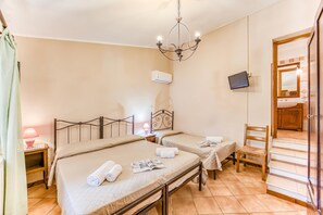 A hotel room with two beds, a chandelier, an air conditioner, a TV, and a staircase.
