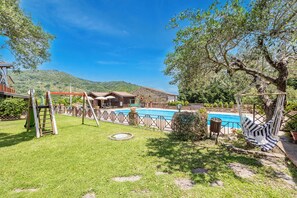 Ein Garten mit Swimmingpool, Hängematte und Schaukel.