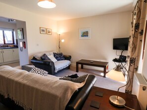 Un salon avec un canapé, une table basse, un téléviseur et une lampe.