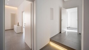 Un couloir moderne avec un escalier, un radiateur et un petit meuble.