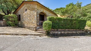 A stone building with a tiled roof, a small arched entrance, and steps leading up to it.
