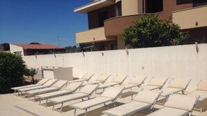 A poolside area with multiple sun loungers arranged in rows.