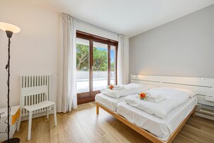 A bedroom with a bed, a chair, a radiator, and a window with curtains.
