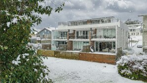 A modern multi-story building with large windows, a brick facade, and a flat roof. - Edge One - Dog Friendly (Jindabyne)