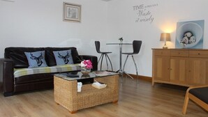 Ein möbliertes Zimmer mit einer Couch, einem kleinen Tisch, einem Schrank und einer Wand mit einer dekorativen Schrift.