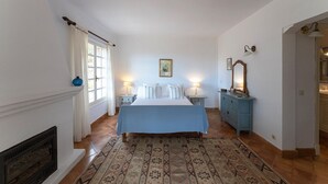 A bedroom with a bed, bedside tables, a dresser, a mirror, and a fireplace. - Casa Perdita, ideal for family and relaxed vacations (Deiá)