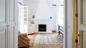 A hallway leading to a living room with a fireplace, a patterned rug, and a bench. - Casa Perdita, ideal for family and relaxed vacations (Deiá)