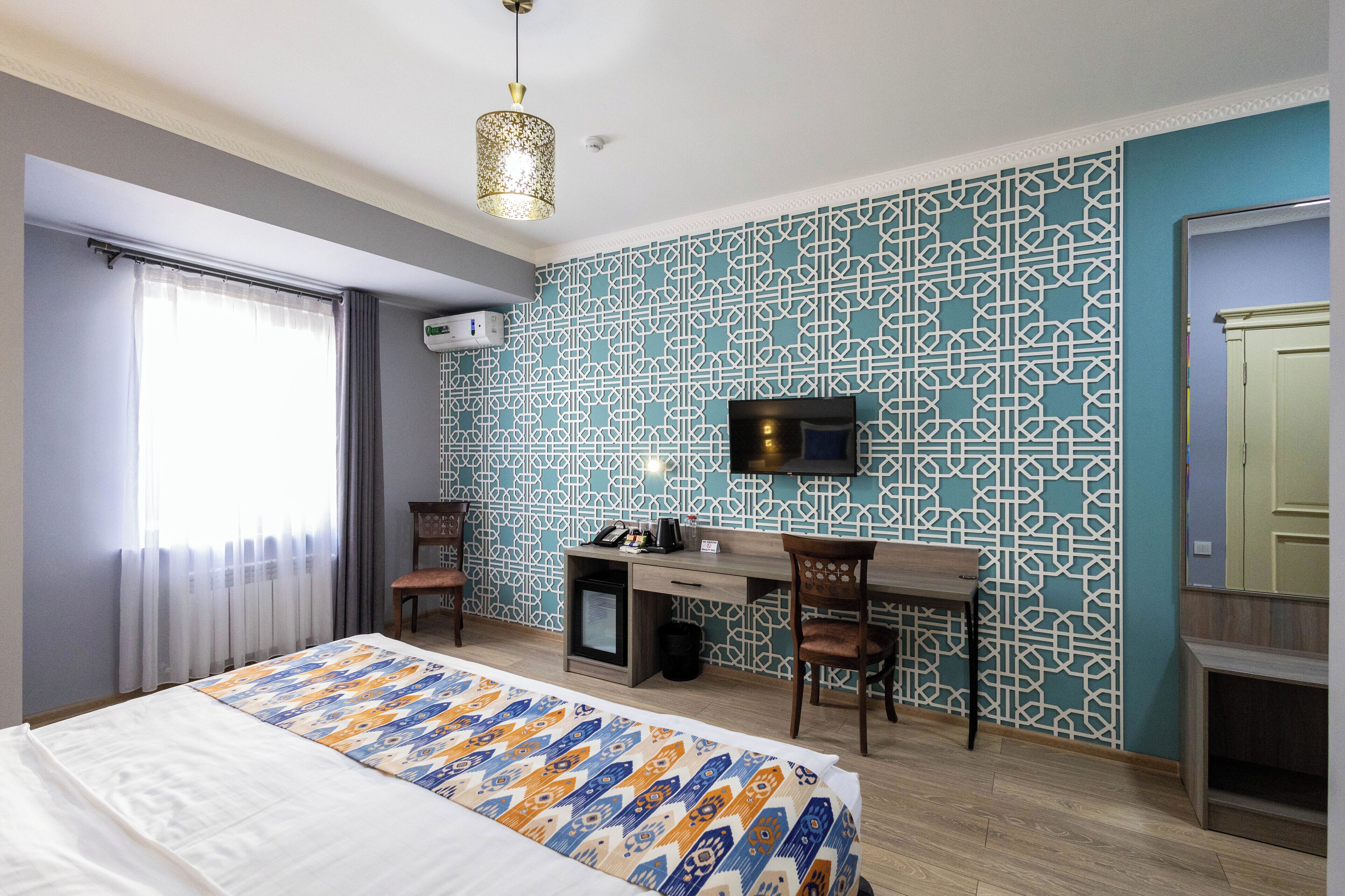 Ein Hotelzimmer mit Bett, Schreibtisch und Fernseher.