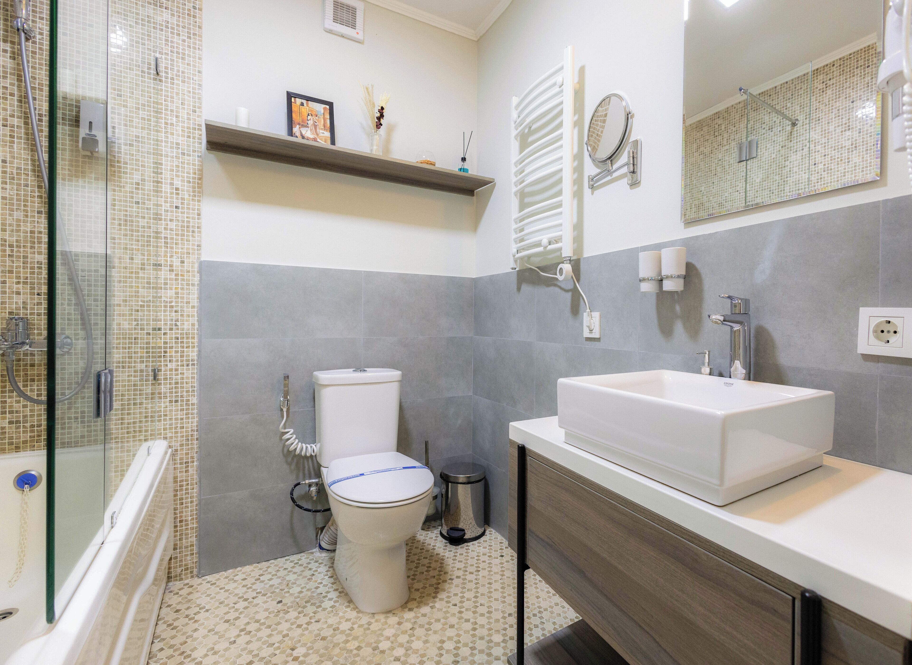 A modern bathroom with a glass shower enclosure, a toilet, a sink, and a mirror.