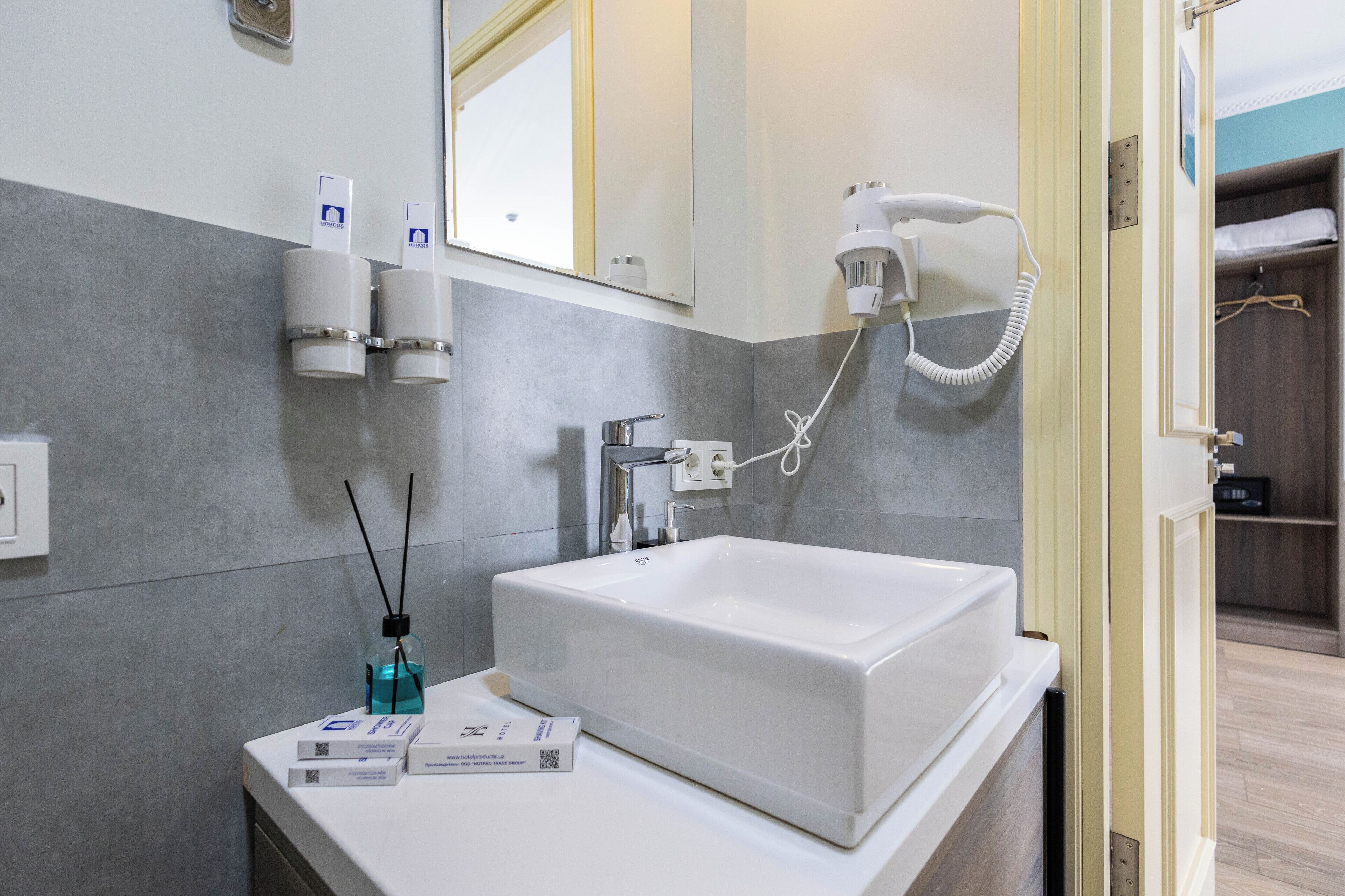 A modern bathroom with a white sink, a handheld hair dryer, and a mirror.