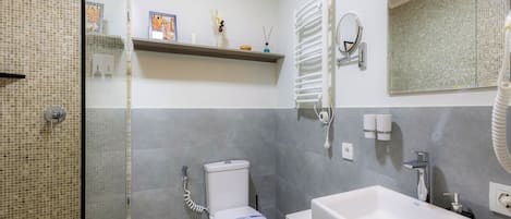 Une salle de bain moderne avec une douche à parois de verre, des toilettes, une baignoire et un meuble-lavabo avec un miroir.