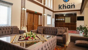 Eine Hotelhalle mit Empfangstresen, Sofas und einem Tisch mit Blumen.