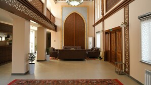 Eine geräumige Lobby mit einer zentralen Sitzecke, einer dekorativen Decke und einer großen Holztür.