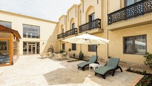 A courtyard with lounge chairs, a table, and an umbrella.