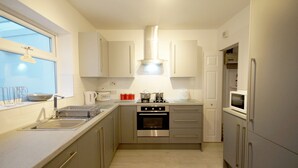 Een moderne keuken met roestvrijstalen apparatuur, witte kasten en een raam dat zorgt voor natuurlijk licht.