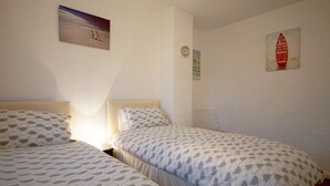 Een slaapkamer met twee bedden, een wandklok en twee schilderijen.