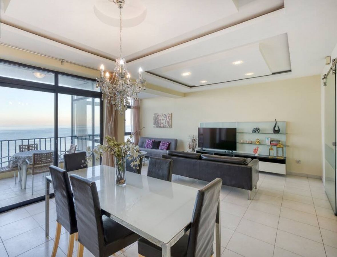 Un salon moderne avec un coin repas, de grandes fenêtres et un balcon offrant une vue dégagée.