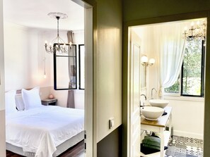 A bedroom with a bed, bedside table, and a chandelier. - Le Chat Vert - Gîte de Charme**** (Saint André)