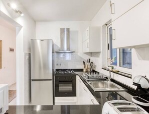 A modern kitchen with stainless steel appliances, a gas stove, and a built-in oven. - Centre APT in St Julians/PV with spacious living (San Ġiljan)