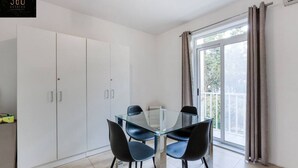 A modern kitchen with white cabinets, a glass dining table, and black chairs. - Spacious, central APT in Paceville/St Julians. (San Giljan)