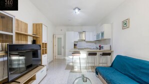 A modern living room with a flat-screen TV, a blue sofa, and a glass coffee table. - Spacious, central APT in Paceville/St Julians. (San Giljan)