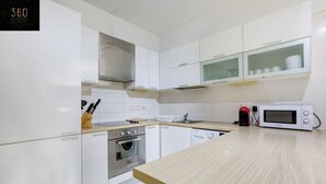 A modern kitchen with white cabinets, stainless steel appliances, and a wooden countertop. - Spacious, central APT in Paceville/St Julians. (San Giljan)