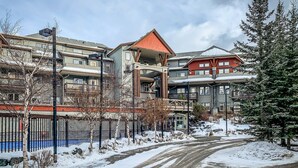 Un immeuble à plusieurs étages, doté d’un toit rouge, entouré d’un paysage enneigé et d’arbres.