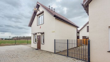 A two-story residential building with a tiled roof, a gated entrance, and a paved driveway.