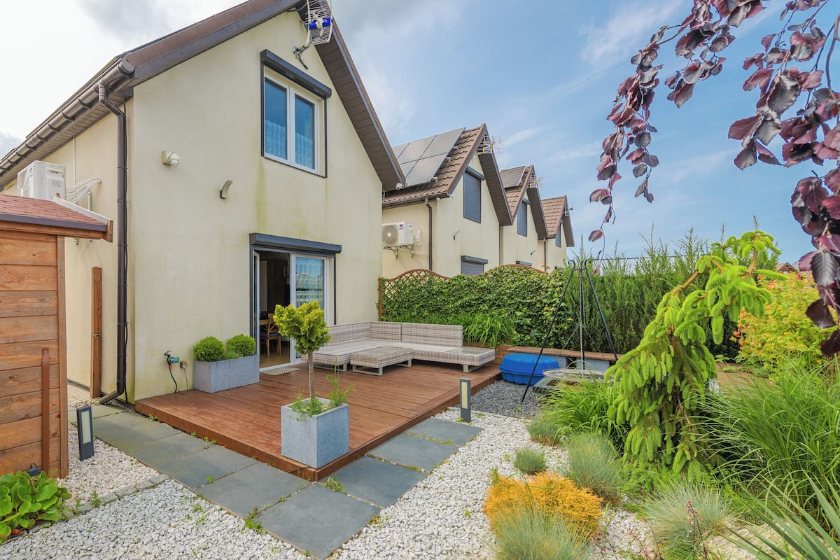 A house with a wooden deck, a small garden, and a shed.