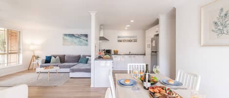 A modern living space with a dining area, kitchen, and a sofa set.