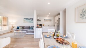 A modern living space with a dining area, kitchen, and a sofa set.