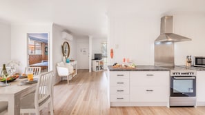 Una cocina moderna con armarios blancos, horno empotrado y microondas.