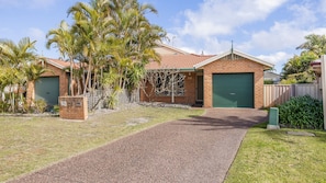 A residential property with a paved driveway, a brick house, and a green garage door.