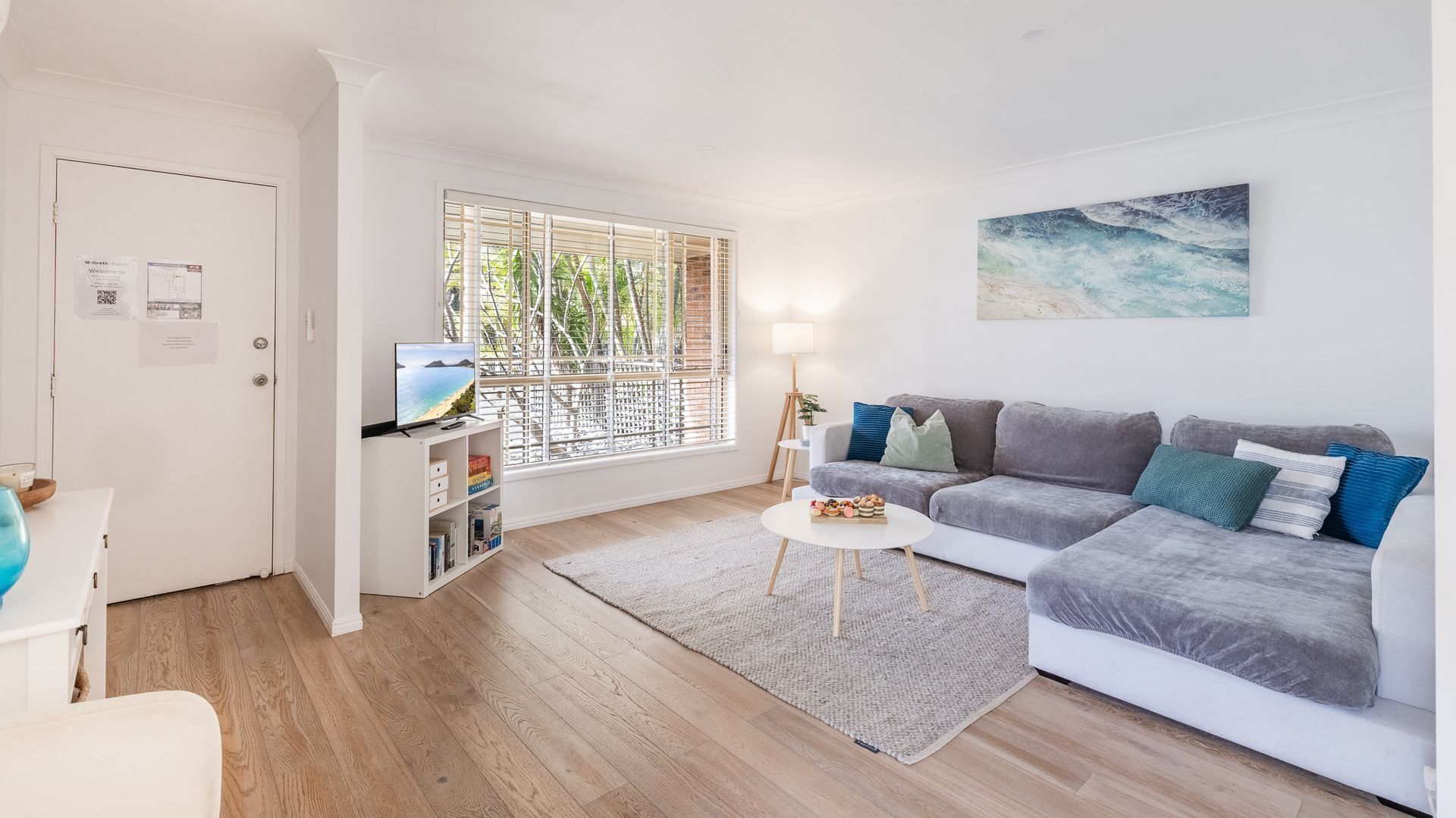 A modern living room with a grey sofa, a coffee table, and a TV on a stand.