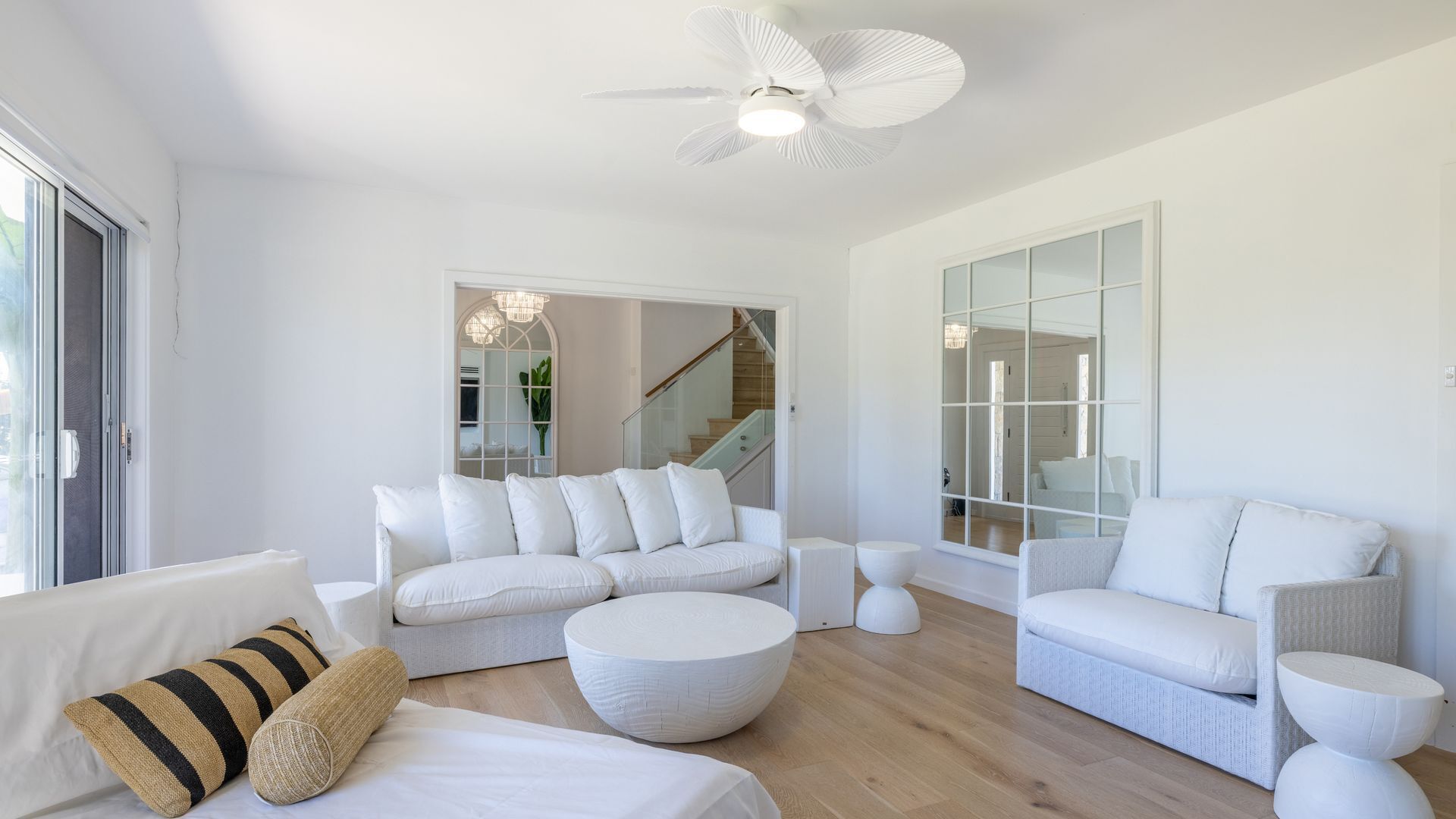 A modern living room with a white sofa set, a round coffee table, and a white side table.
