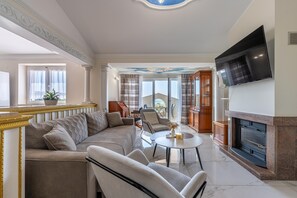 A spacious living room with a large sectional sofa, a fireplace, and a flat-screen TV mounted on the wall.