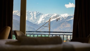 Un lit donnant sur des montagnes enneigées, avec une vue par la fenêtre.