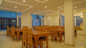 Un espace repas avec des tables et des chaises en bois, de grandes fenêtres et un design moderne au niveau du plafond.