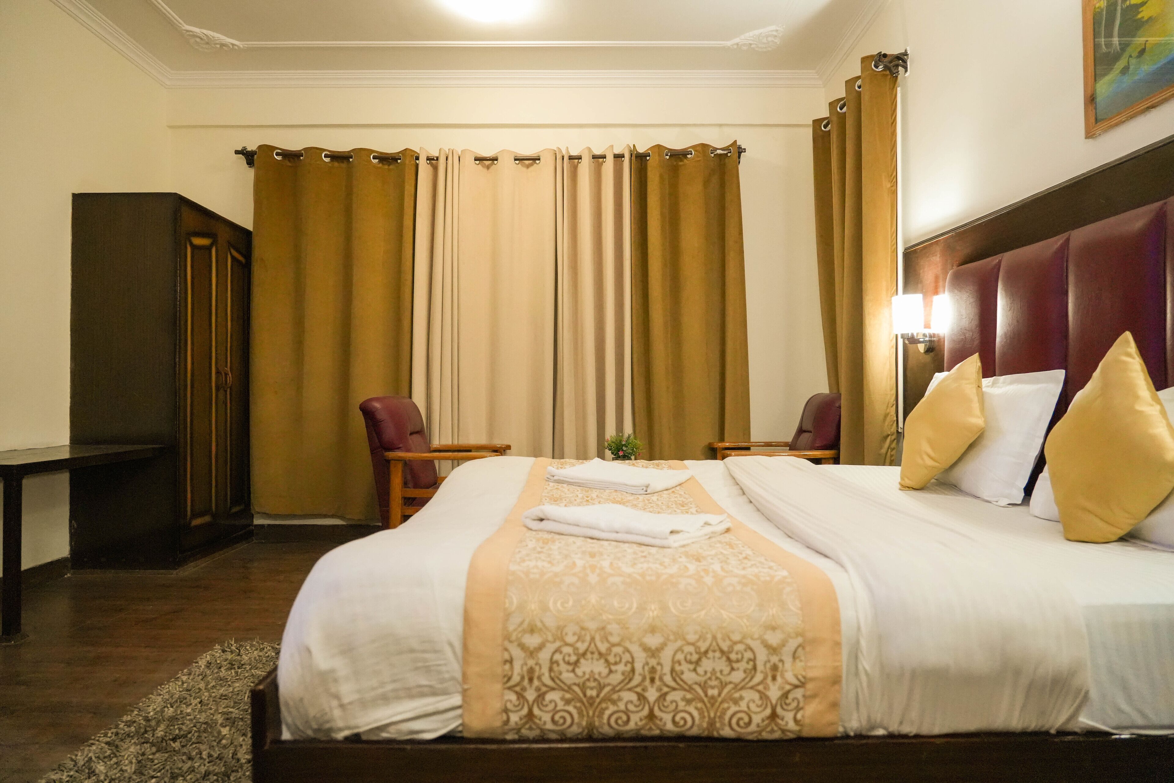 Een hotelkamer met een groot bed, twee stoelen, een bureau en een kledingkast.