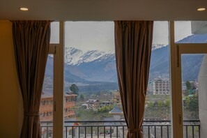 Habitació amb una finestra gran que dona a un paisatge muntanyós, amb arquitectura tradicional i vista a les muntanyes.