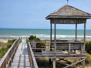 Un mirador de madera con techo de celosía que da a la playa.