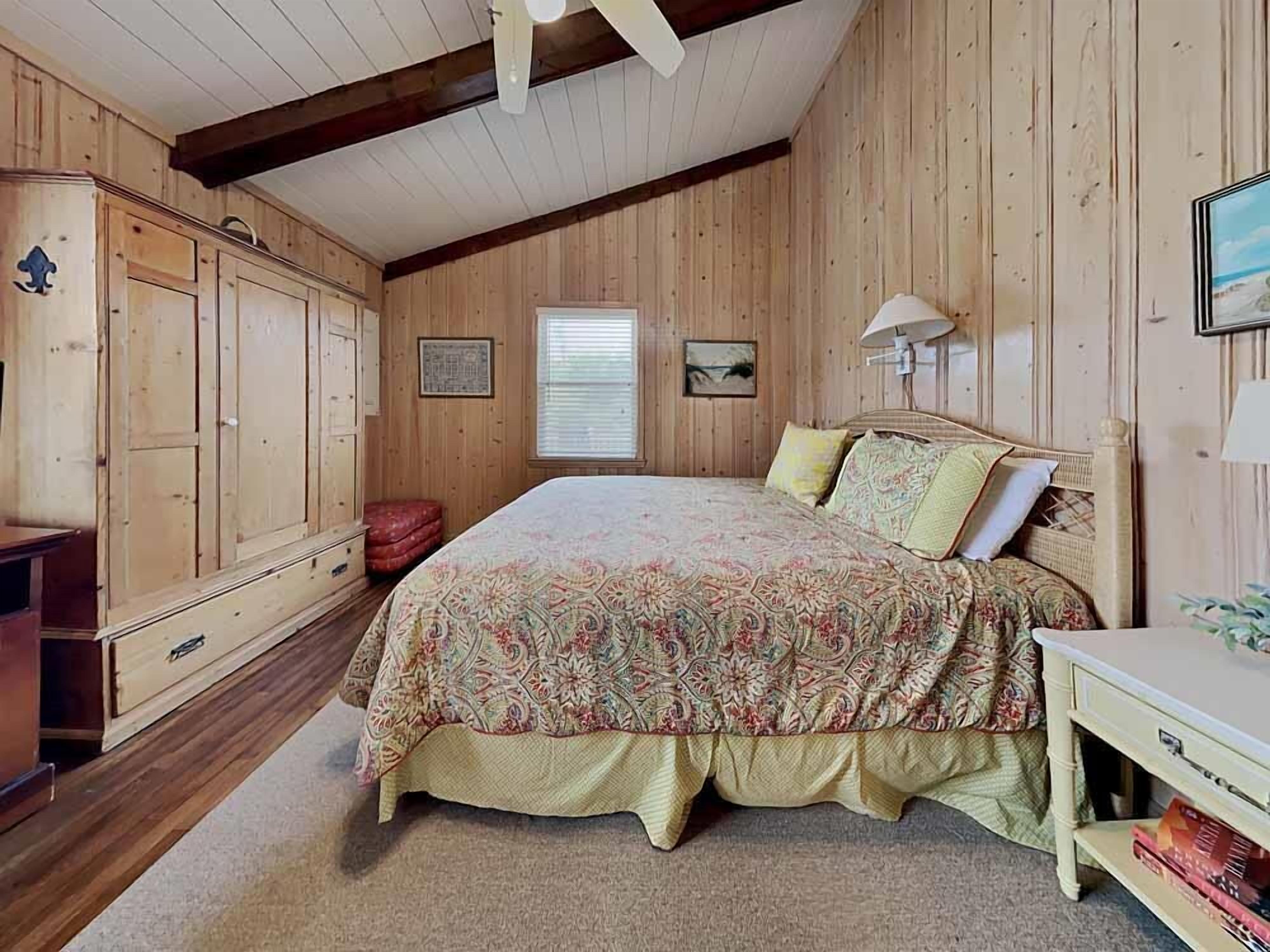 Una camera da letto con un letto grande, pareti in legno, una cassettiera e un comodino.