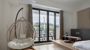 A modern hotel room with a hanging chair, a bed, a TV, and a balcony with a table and chairs. - YUJING NU TIME (Tainan)