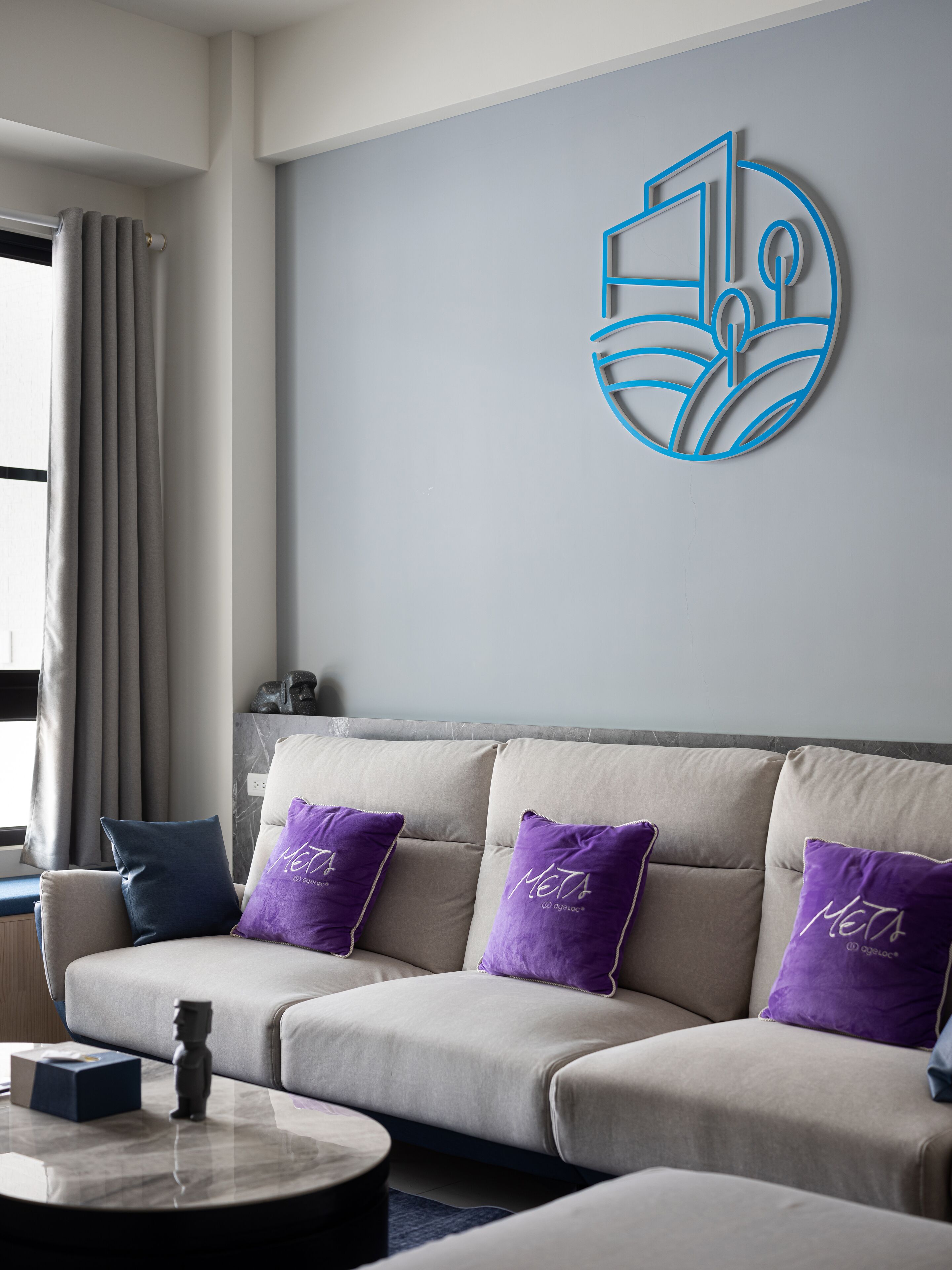 A modern living room with a beige sofa, purple cushions, a coffee table, and a wall art piece.