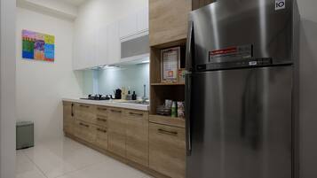 A modern kitchen with a stainless steel refrigerator, wooden cabinets, and a tiled floor.