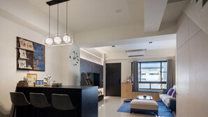 A modern living space with a kitchen area, a dining table with chairs, a sofa, and a large window providing a view of the outside. - YUJING NU TIME (Tainan)
