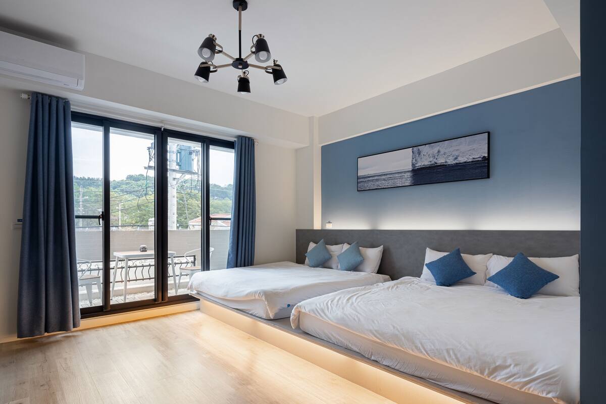 Habitación de hotel moderna con dos camas, un balcón y vistas al exterior.