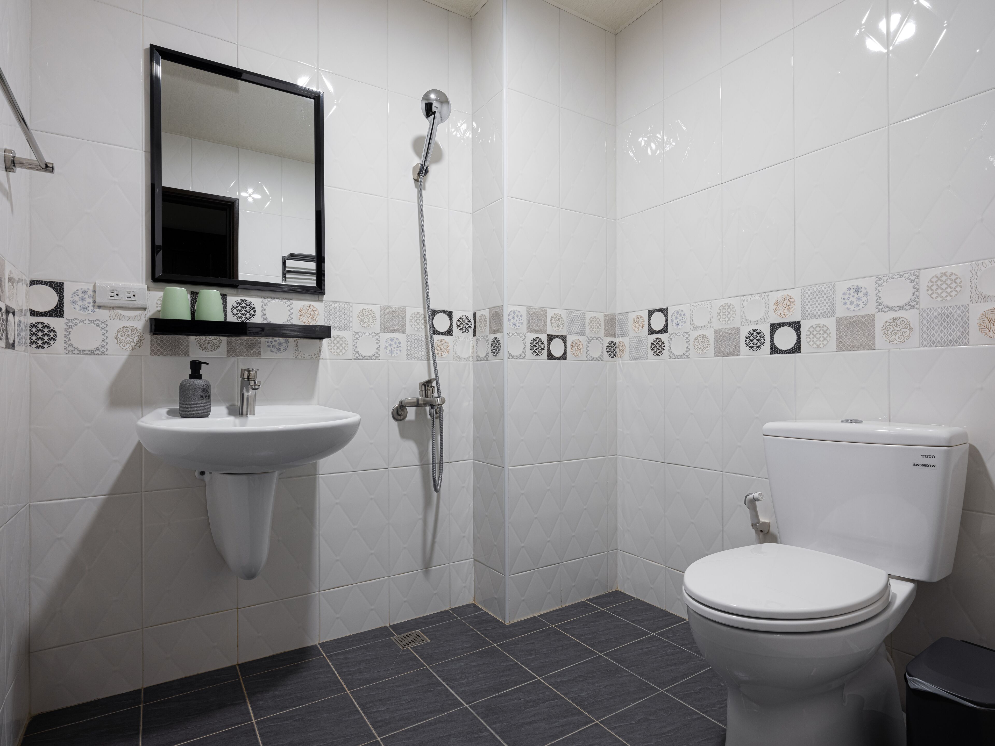 A modern bathroom with a white sink, mirror, and toilet.